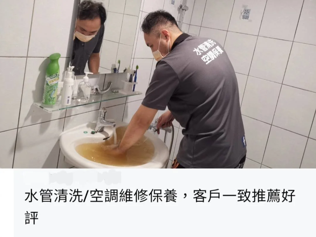 A technician cleaning a sink filled with brown water in a bathroom, wearing a grey uniform and a mask, with a mirror, bottles, and toiletries on the sink shelf.