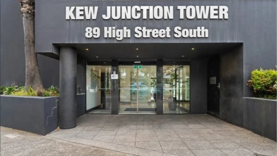 Glass entrance doors beneath the Kew Junction Tower sign