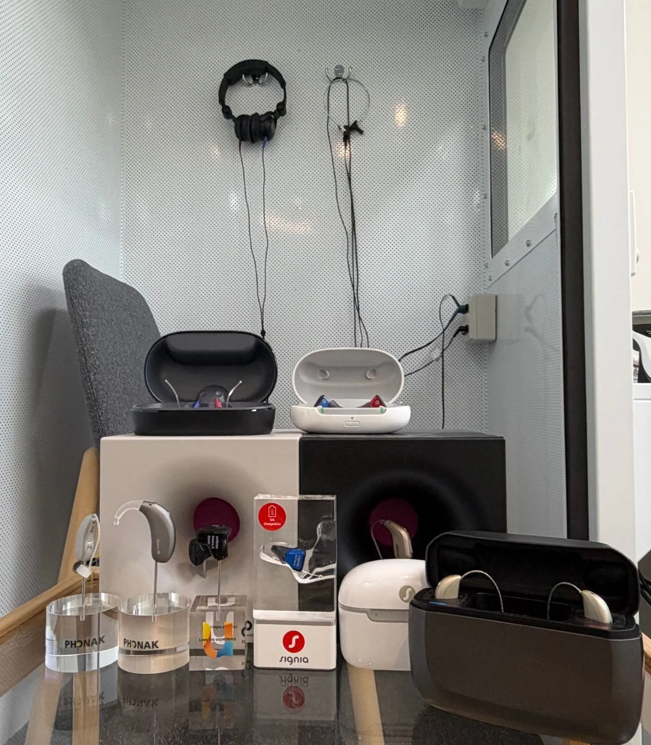 Hearing aids and charging cases on display beside the hearing test booth at the Kew clinic