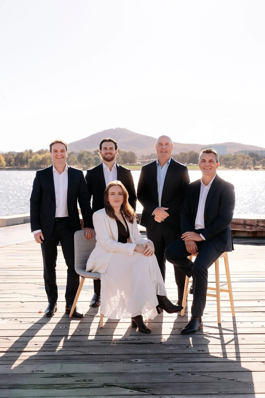 Up Wealth financial advisers financial advice Canberra group photo professionally dressed photograph outdoors near a lake with a mountain in the background, posing for a photo during daytime.