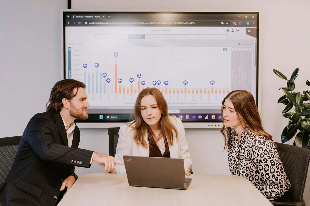 Up Wealth financial advisers financial planning for high-income professionals people sitting at a meeting table with a large screen behind them displaying a graph.