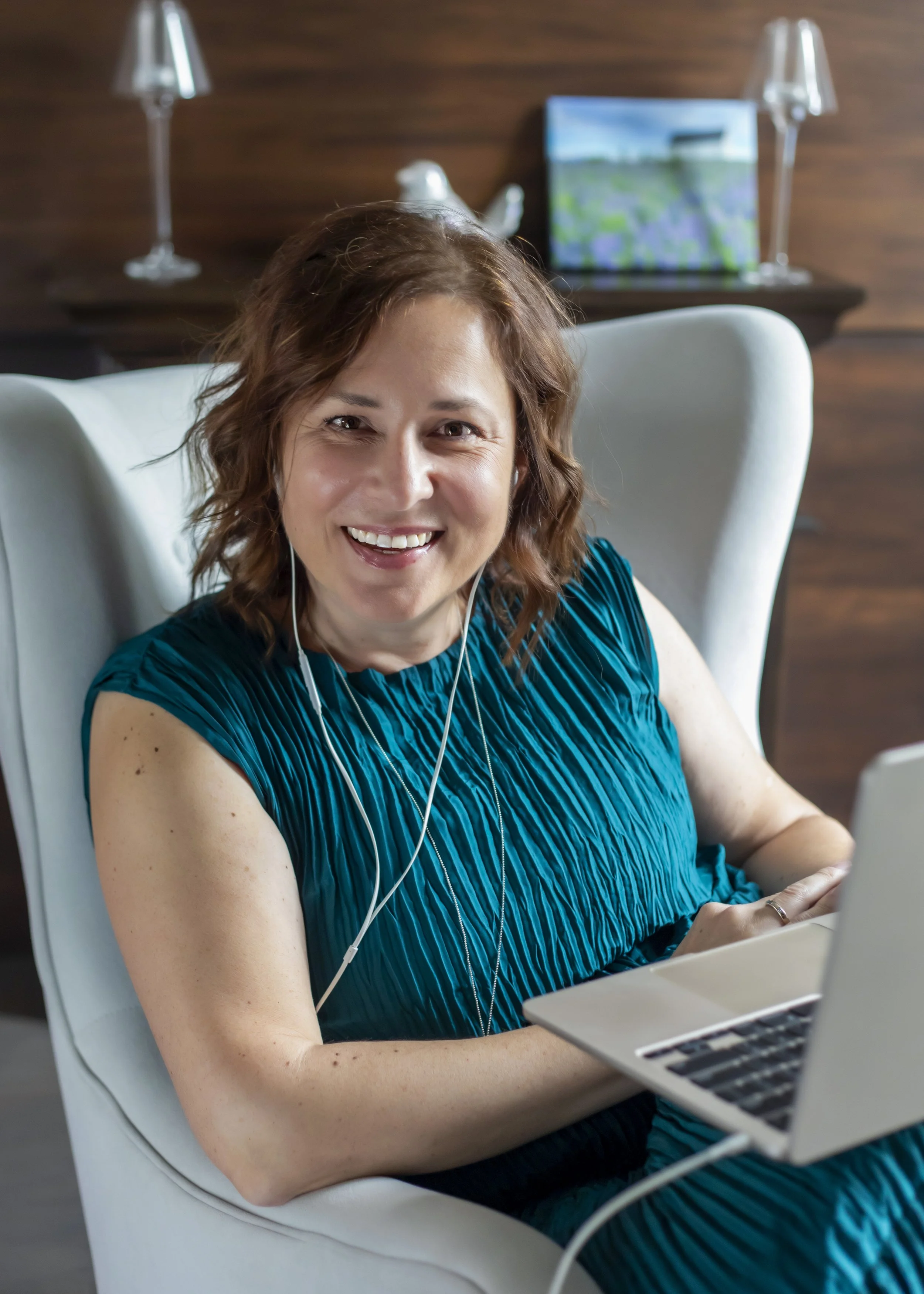 Marcela Kratochvilova, life and career reinvention coach, smiling while working on a laptop in a white chair