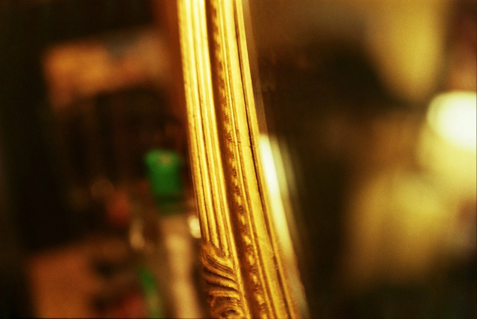 Close-up of a gold ornate picture frame with blurred reflection.
