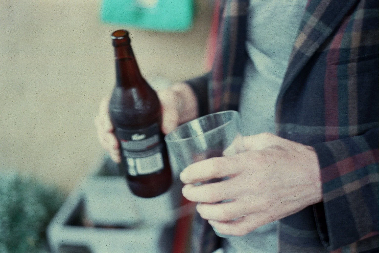 Person pouring a beverage from a brown bottle into a clear cup