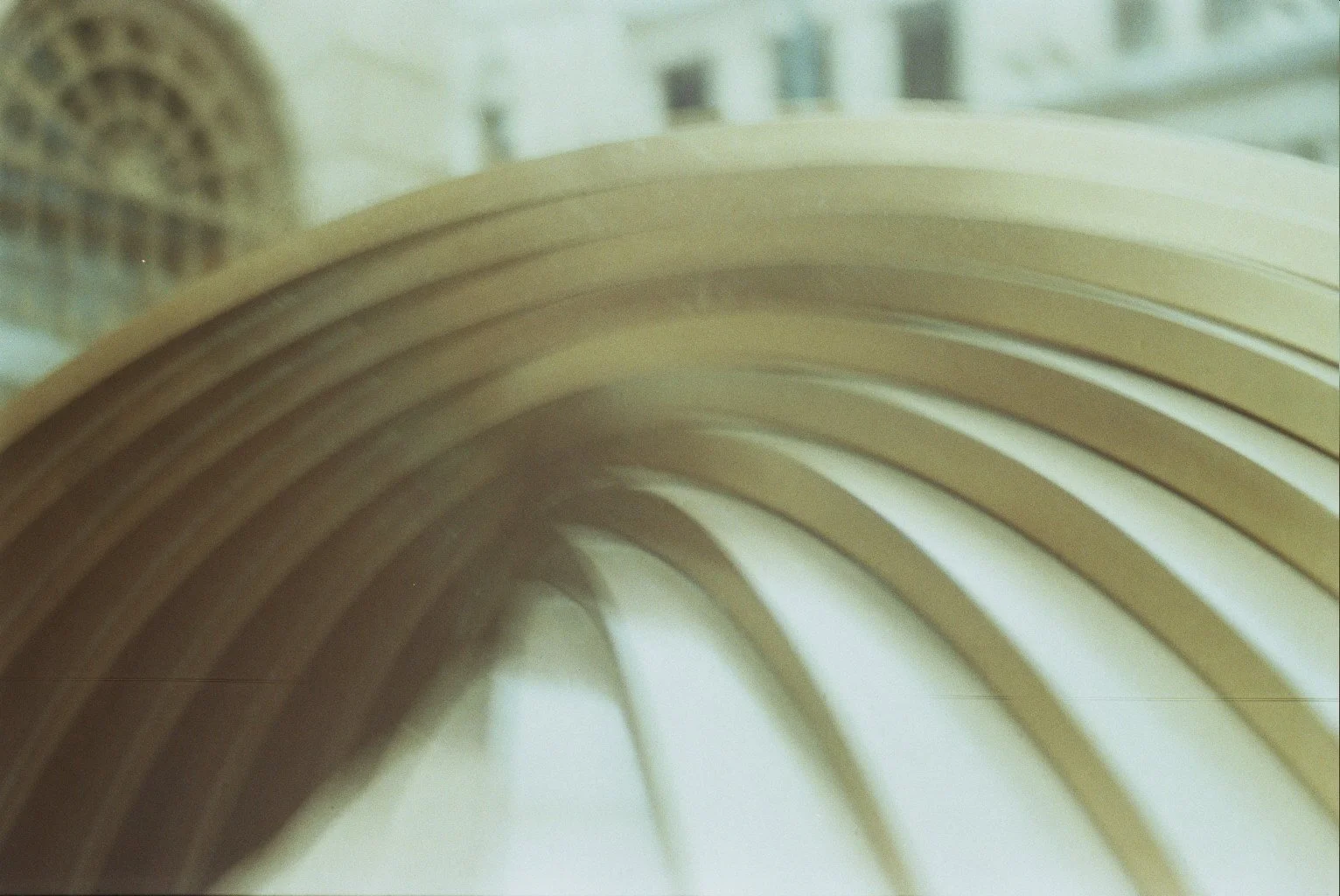 Close-up of stacked wooden bookends or shelves with windows and blurred buildings in the background.