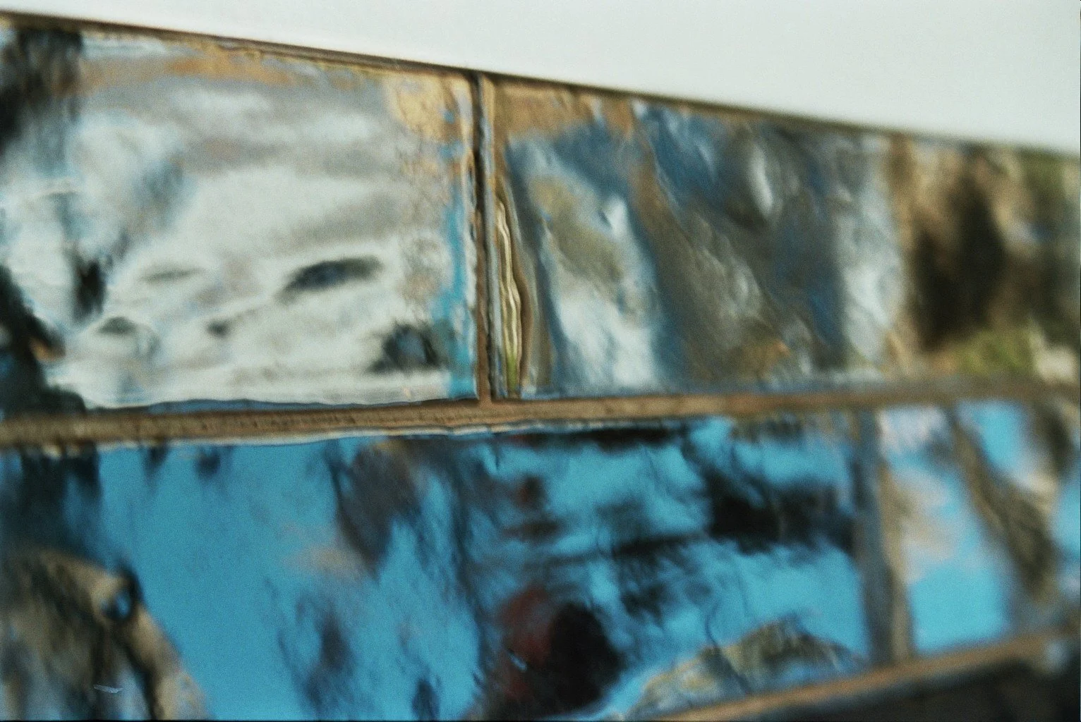 Close-up of a stack of metallic beer cans, with visible dents and scratches, reflecting light.