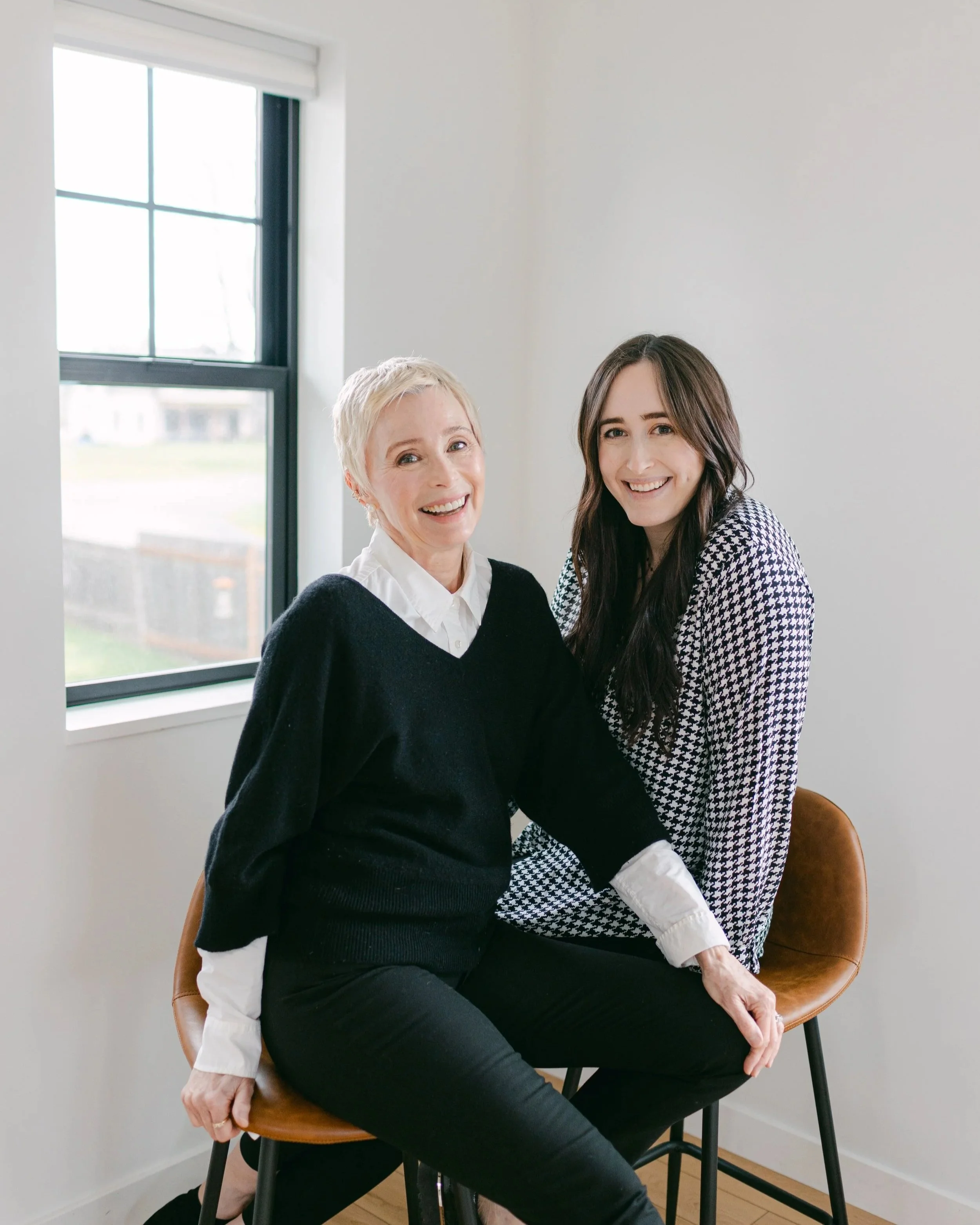 Fiona and Kate of Weddings Unlocked sitting on a chair by a window