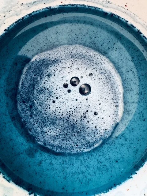 Blick in eine blaue Wanne mit Seifenblasen und Schaum.