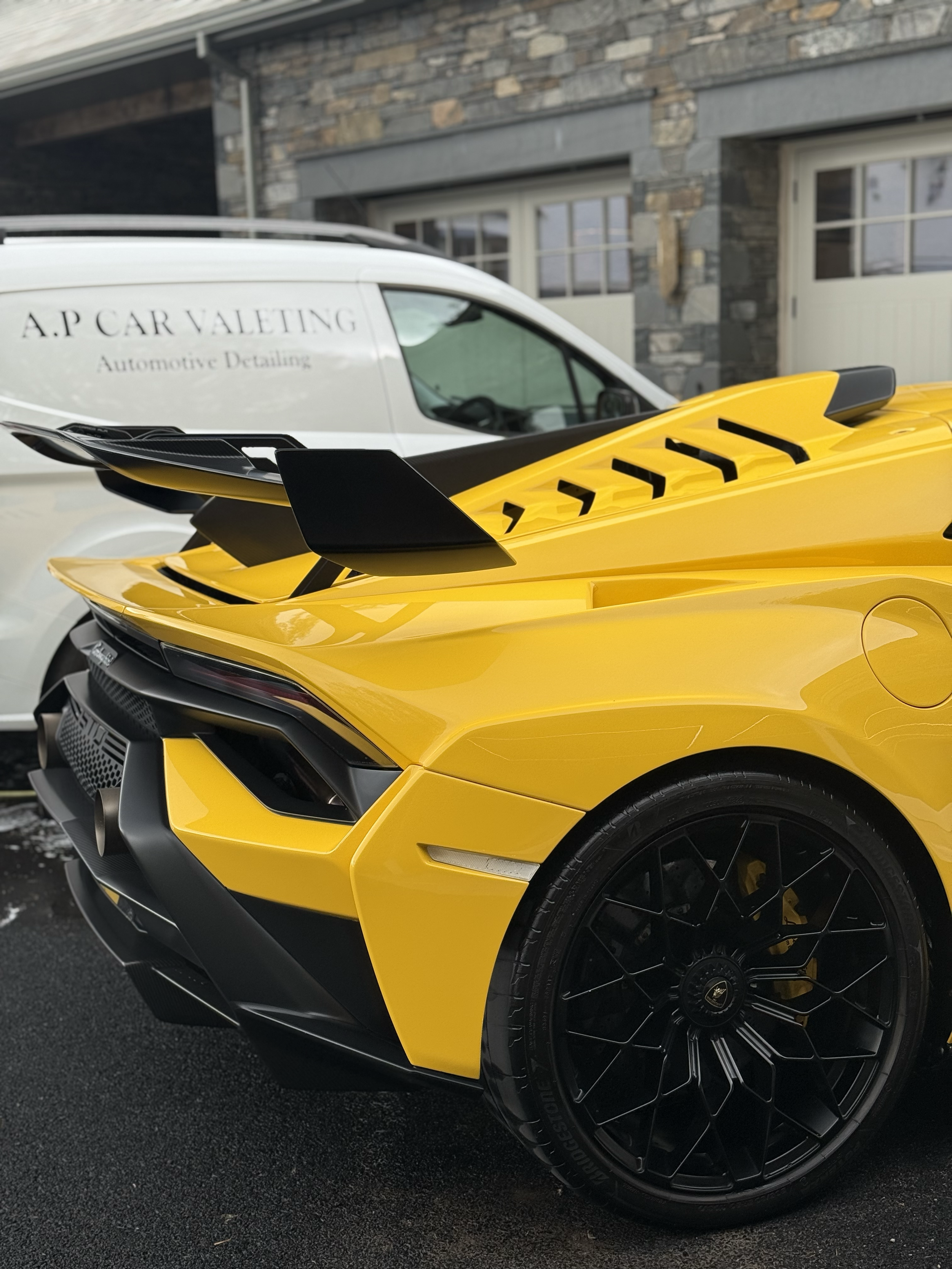 Close-up of a yellow sports car, highlighting the front left side, black wheel with a detailed rim, and black accents near the bumper.
