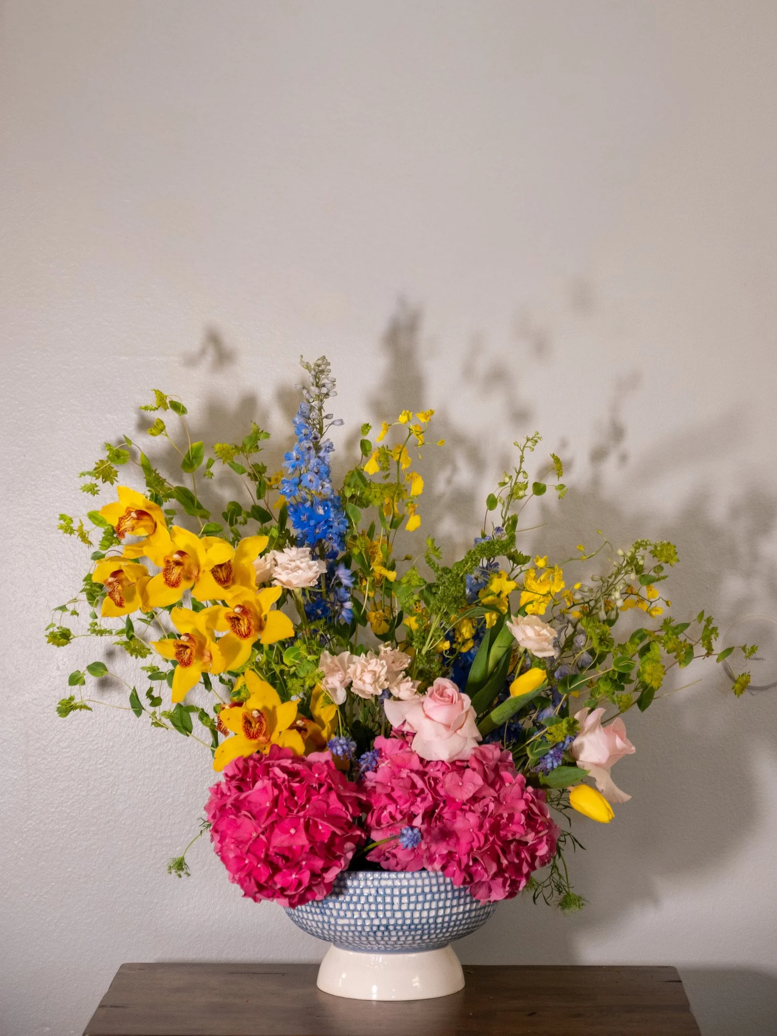 A large floral arrangement in a patterned blue and white vase on a wooden surface.