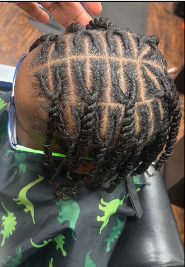 Child with recently styled invisible locs featuring intricate patterns shaved into the scalp.