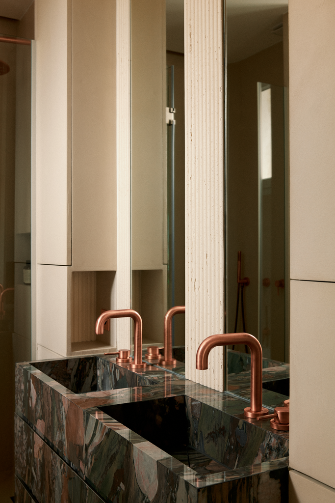 Lavabo en marbre avec robinet en cuivre dans une salle de bain