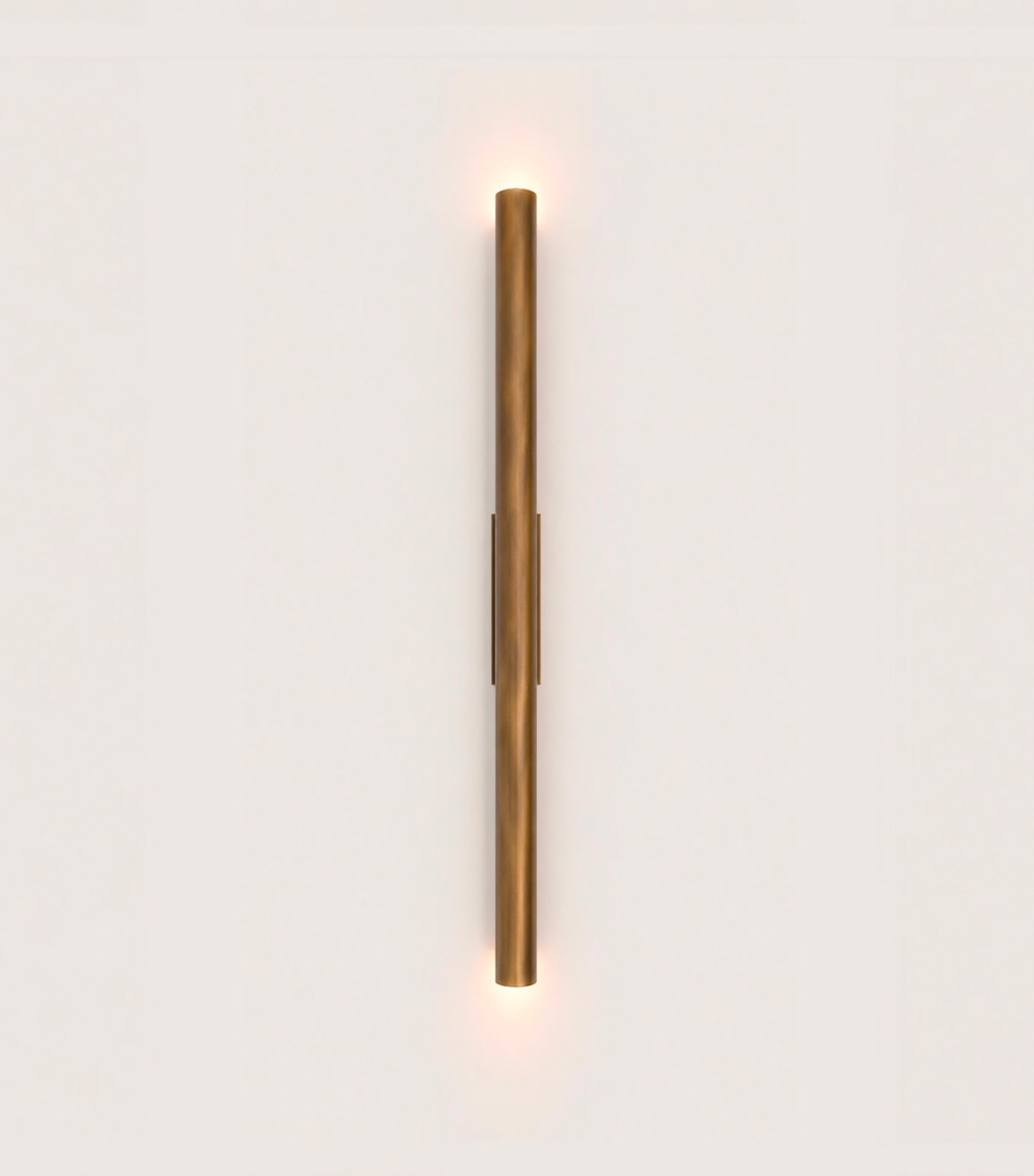 Une lampe murale en forme de tube métallique brun fixée au centre d’un mur blanc.