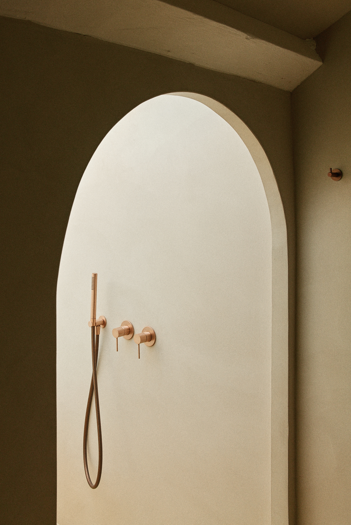 Douche à l'italienne avec un mur blanc, une pomme de douche, un robinet et un distributeur de savon dans une salle de bain minimaliste