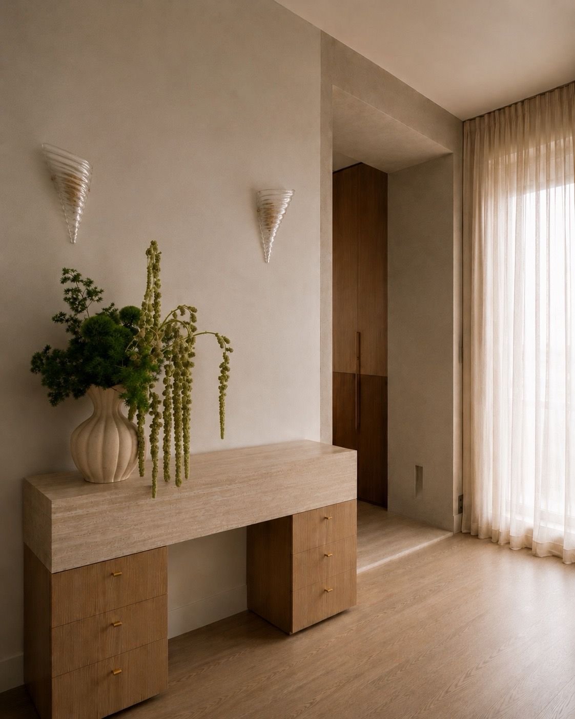 Intérieur minimaliste avec une console en bois clair, une plante dans un vase beige, murs neutres, rideaux en tissu léger, et appliques murales en verre.