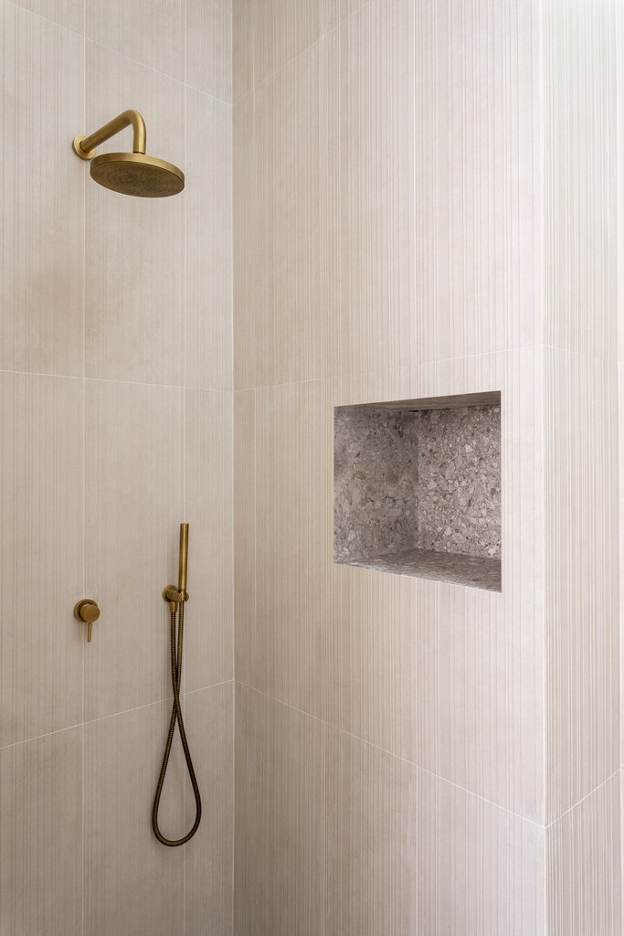 Douche avec tête de douche en métal doré, pomme de douche à main dédiée, niche en murs en pierre