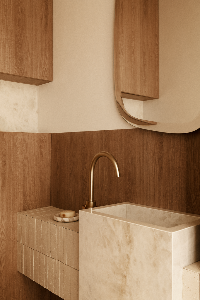 Lavabo en pierre avec robinet en laiton, accessoires en pierre, meuble en bois autour du lavabo, miroir en bois courbé.