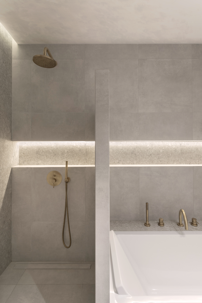 Salle de bain avec une douche à l'italienne, un pommeau de douche rond et une baignoire avec robinetterie en laiton.