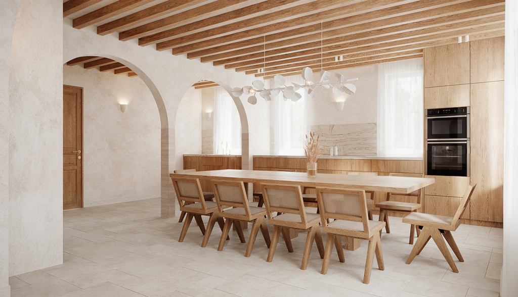 Salle à manger moderne avec table en bois, chaises en bois, plafond en poutres apparentes en bois, chandelier blanc, murs en pierre claire, grands fenêtres avec rideaux blancs, cuisine intégrée en bois avec double four encastré.
