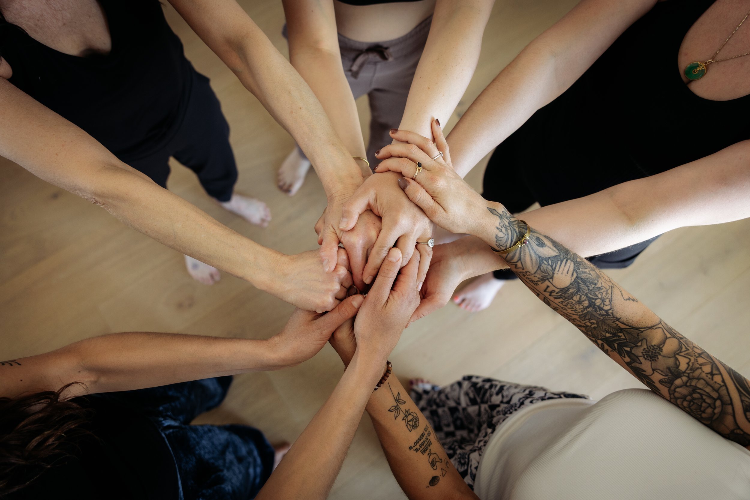 Gathered Hearth community members with hands stacked together