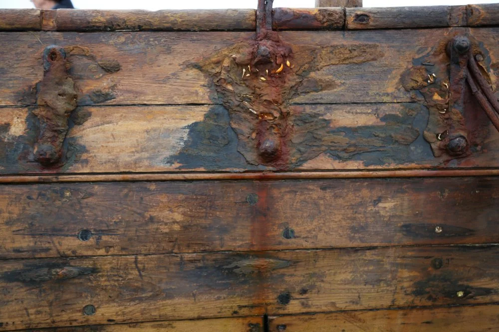 Close-up of old, weathered wooden surface with rusted metal hardware and fasteners.
