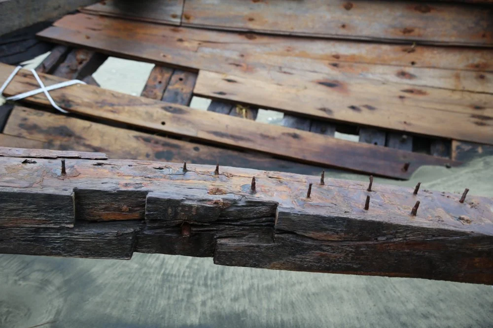 Close-up of damaged, weathered wooden planks with rusty nails, part of a wooden structure.