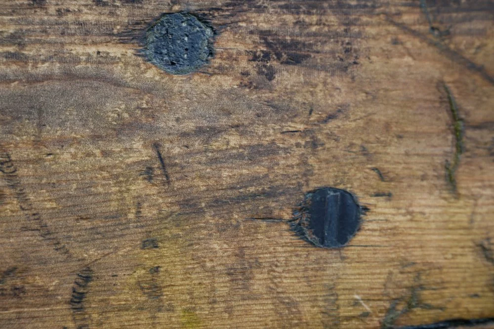 Close-up of a wooden surface with two nail holes.