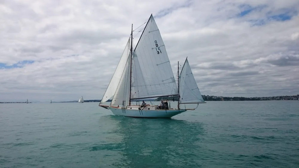 A sailboat on calm water with a cloudy sky.