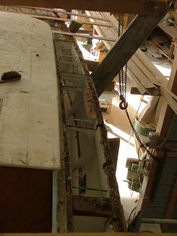 Woodworking workshop with a large workbench, sawdust, a hammer, and shelves filled with wood and tools.