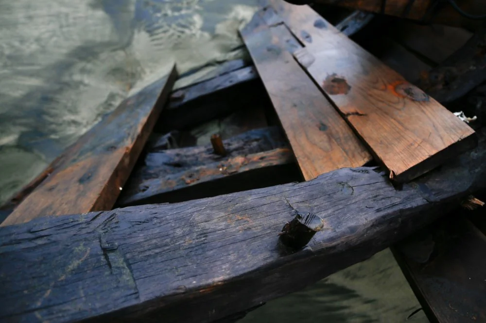 Close-up of a wooden boat in water, showing weathered and aged planks.