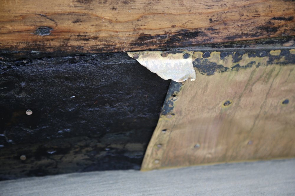 Close-up of damaged wood and metal, with peeling paint and visible rivets.