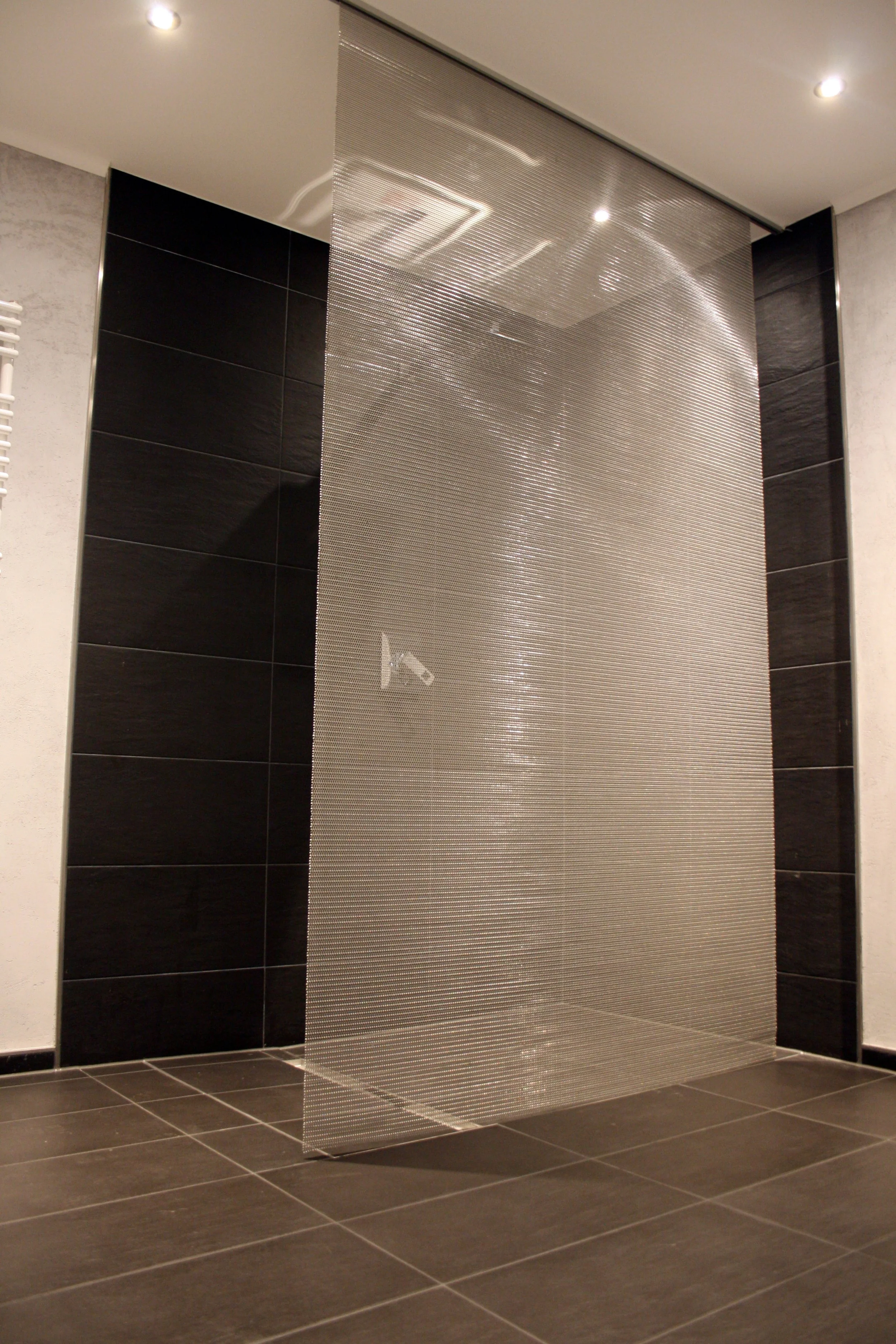 Uranus architectural wire mesh used as a semi‑transparent shower enclosure in a residential bathroom, providing privacy, durability and a clean, modern interior aesthetic.