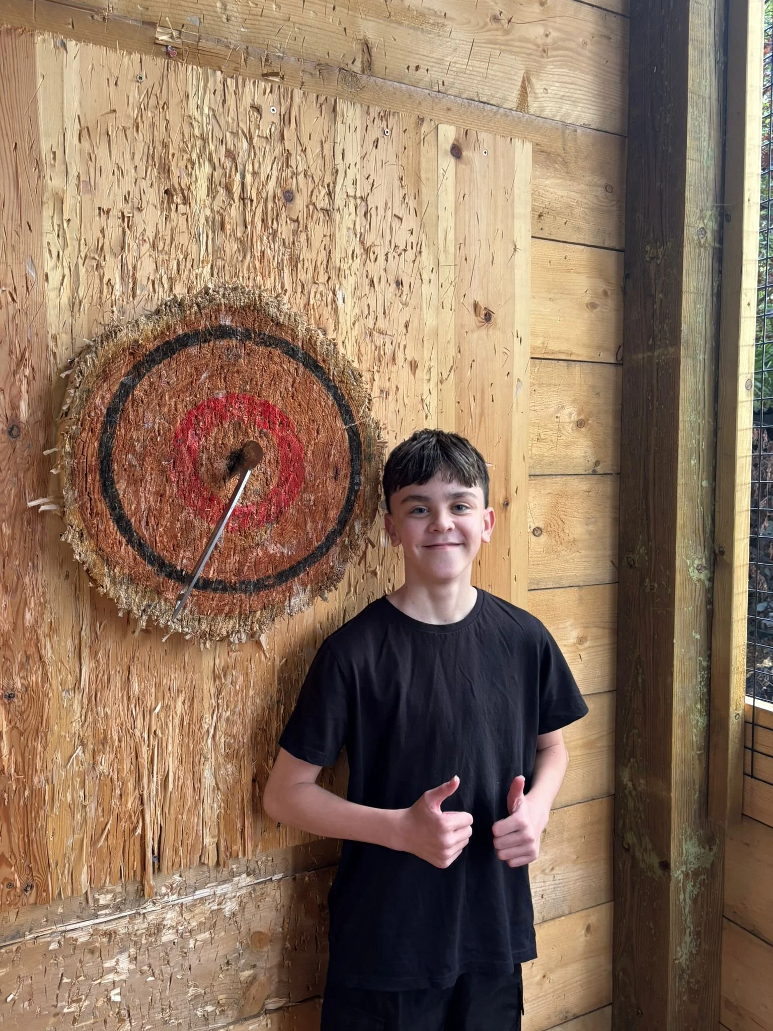 Guest celebrating a bullseye beside a wooden target at Bermuda Blades