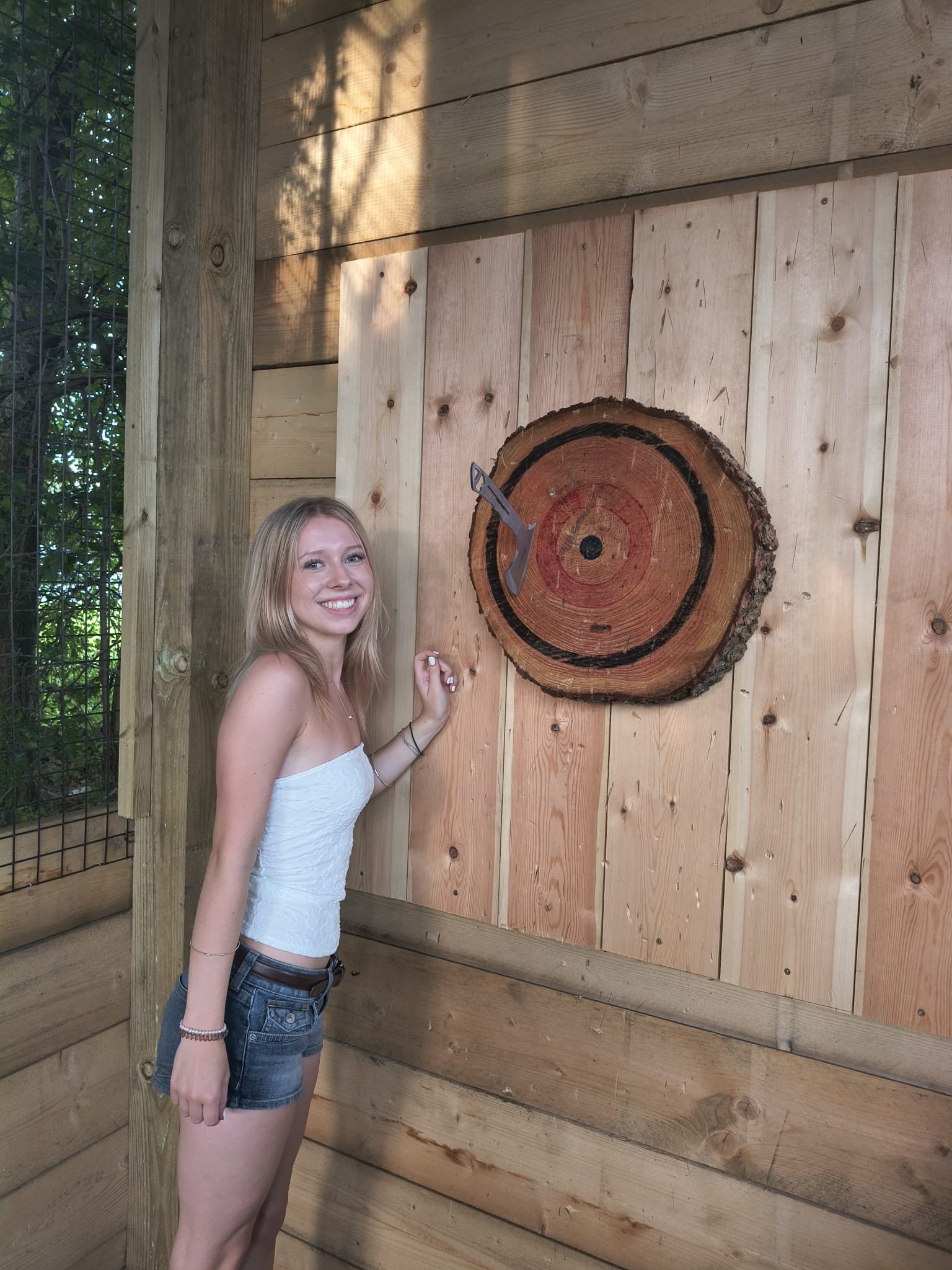 Customer standing in an axe throwing lane with an axe embedded in the target at Bermuda Blades near Bedford.