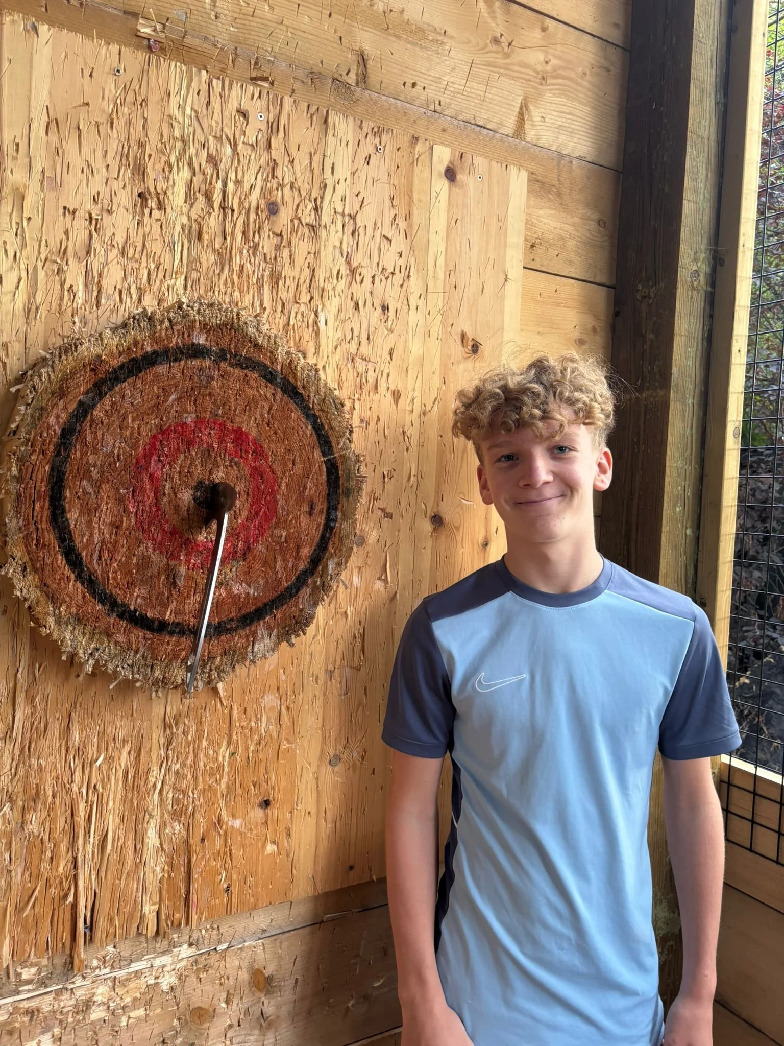 Young guest beside an axe throwing target at Bermuda Blades in Henlow