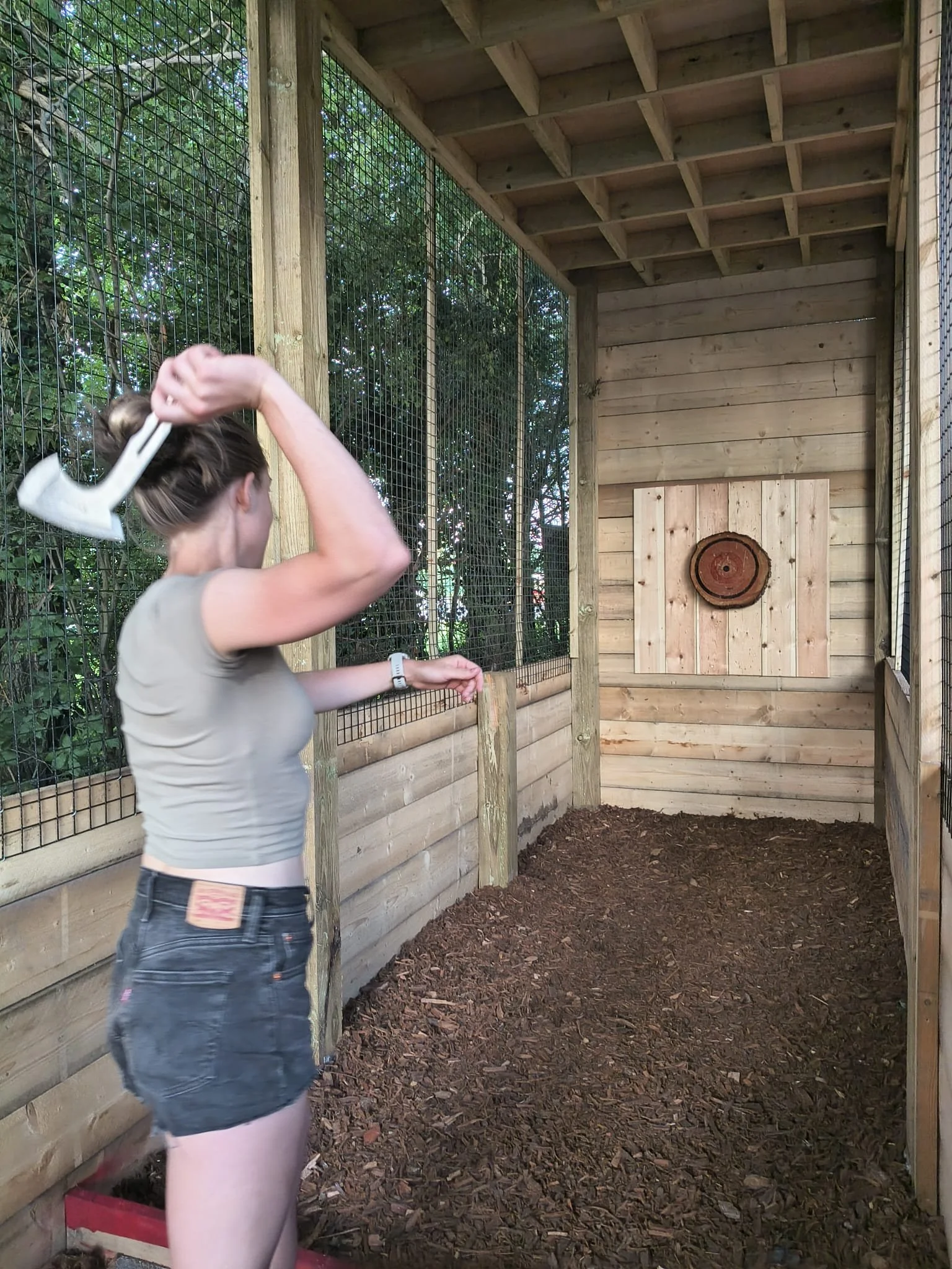 Customer enjoying a covered outdoor axe throwing experience at Bermuda Blades near Bedford and Hitchin.