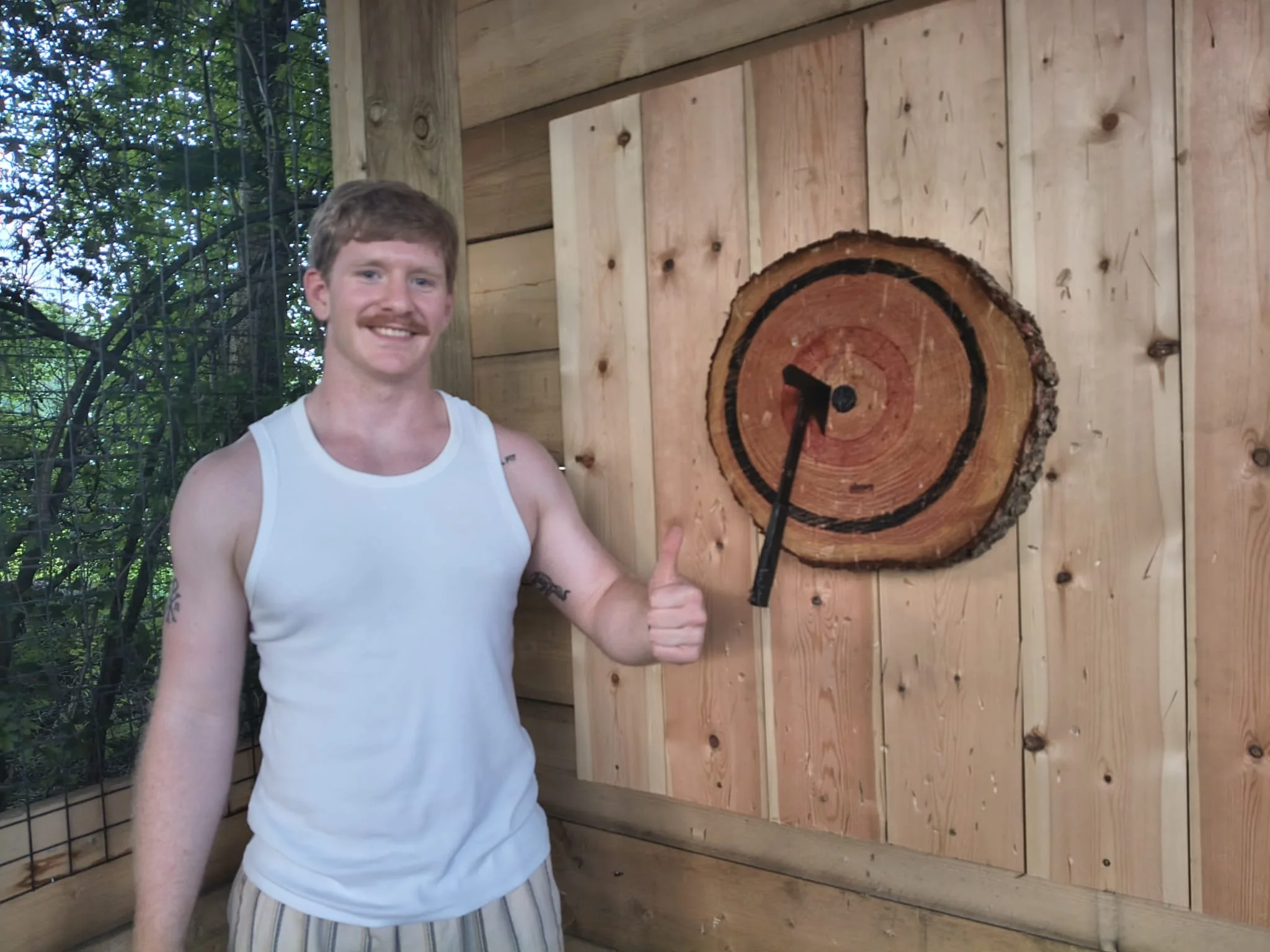 Beginner enjoying a covered outdoor axe throwing experience at Bermuda Blades in Henlow.