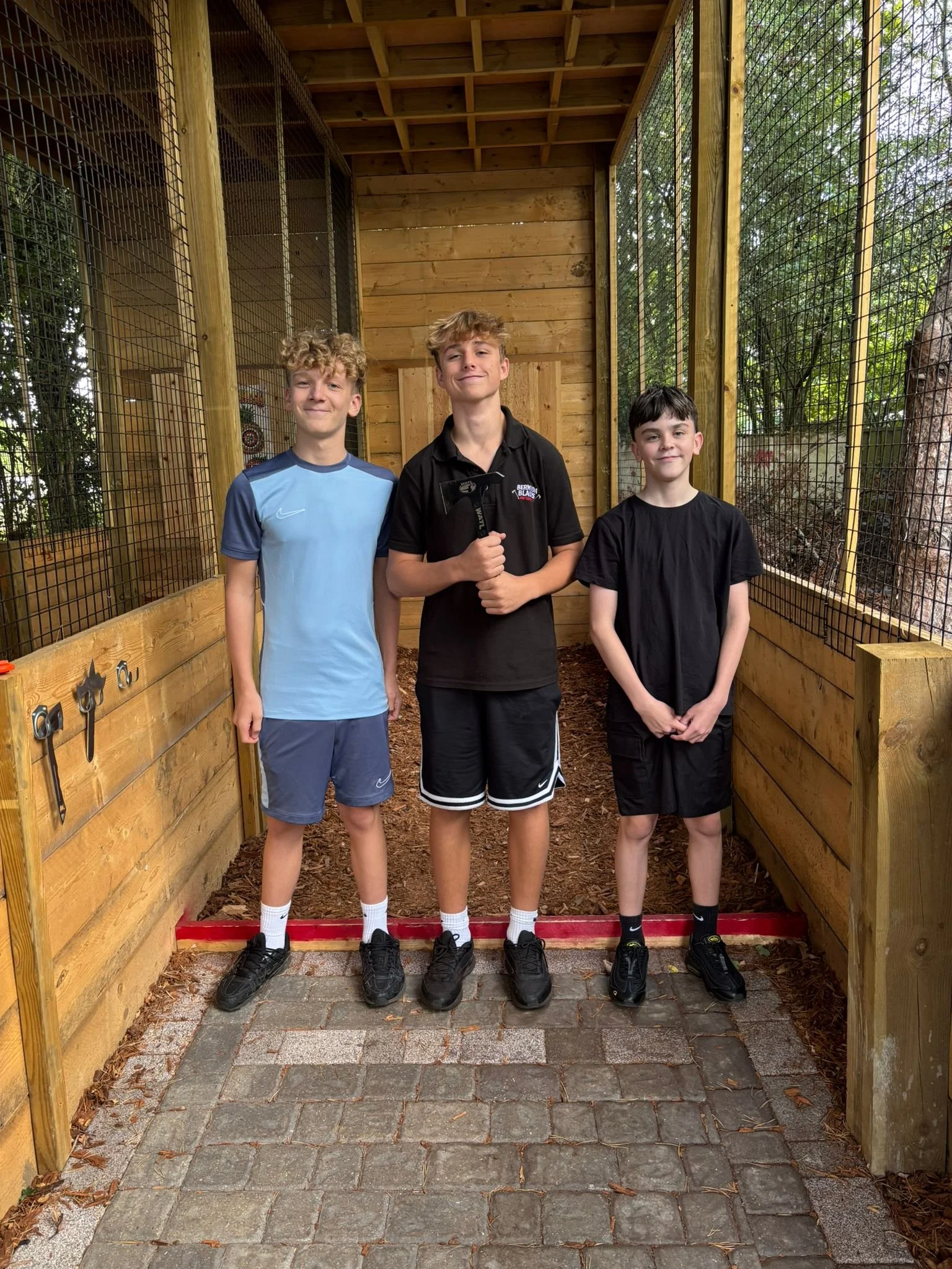 Three young guests enjoying an axe throwing session at Bermuda Blades