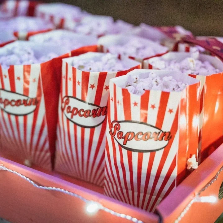 Tüten Popcorn in einer rosa Schachtel, dekoriert mit kleinen Lichtern