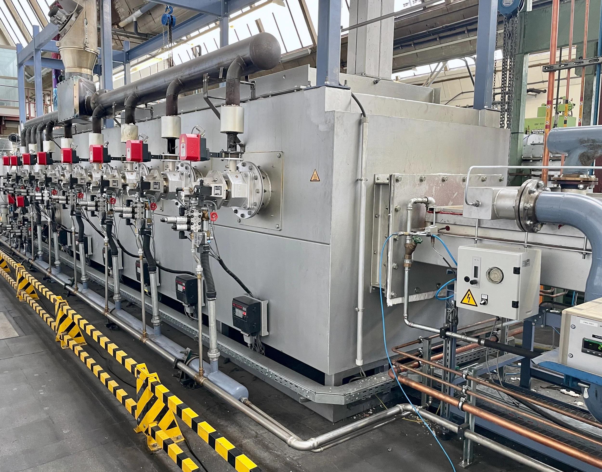 SARNES SInterbandofen mit Reku IOR brennern - Industrielle Maschinentechnik mit Rohren, Ventilen und Steuerelementen in einer Fabrikhalle.