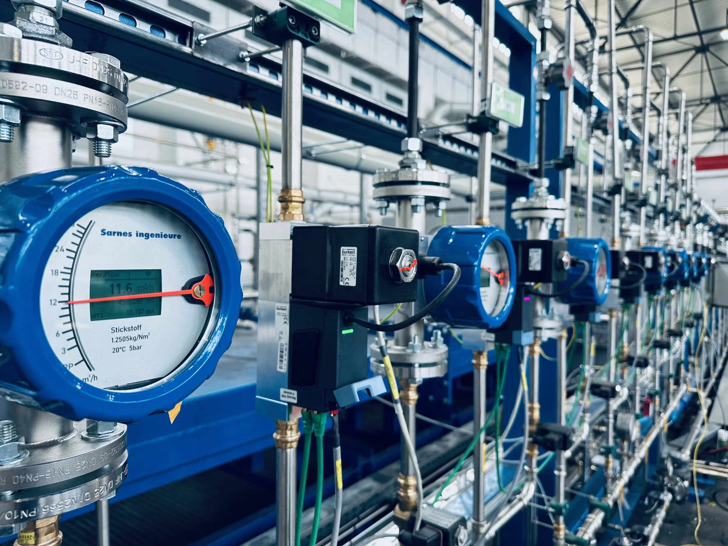 Kühlzone von SARNES mit Strömungsmessern für N2  mit Druckmessgeräten, Rohren und technischen Komponenten in einer Fabrikhalle.
