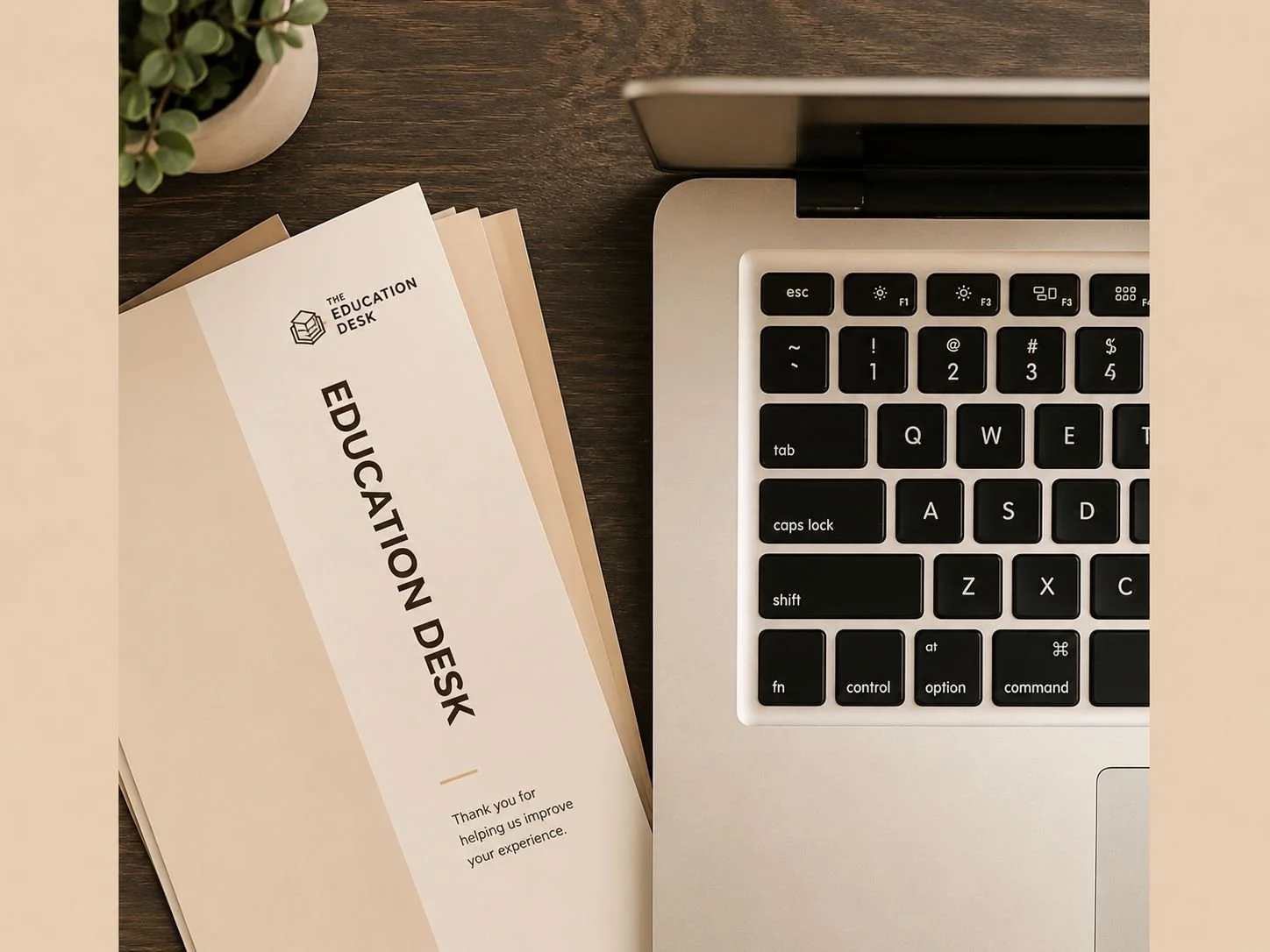 Top view of a workspace with a laptop keyboard, a potted plant, and an 'Education Desk' brochure.