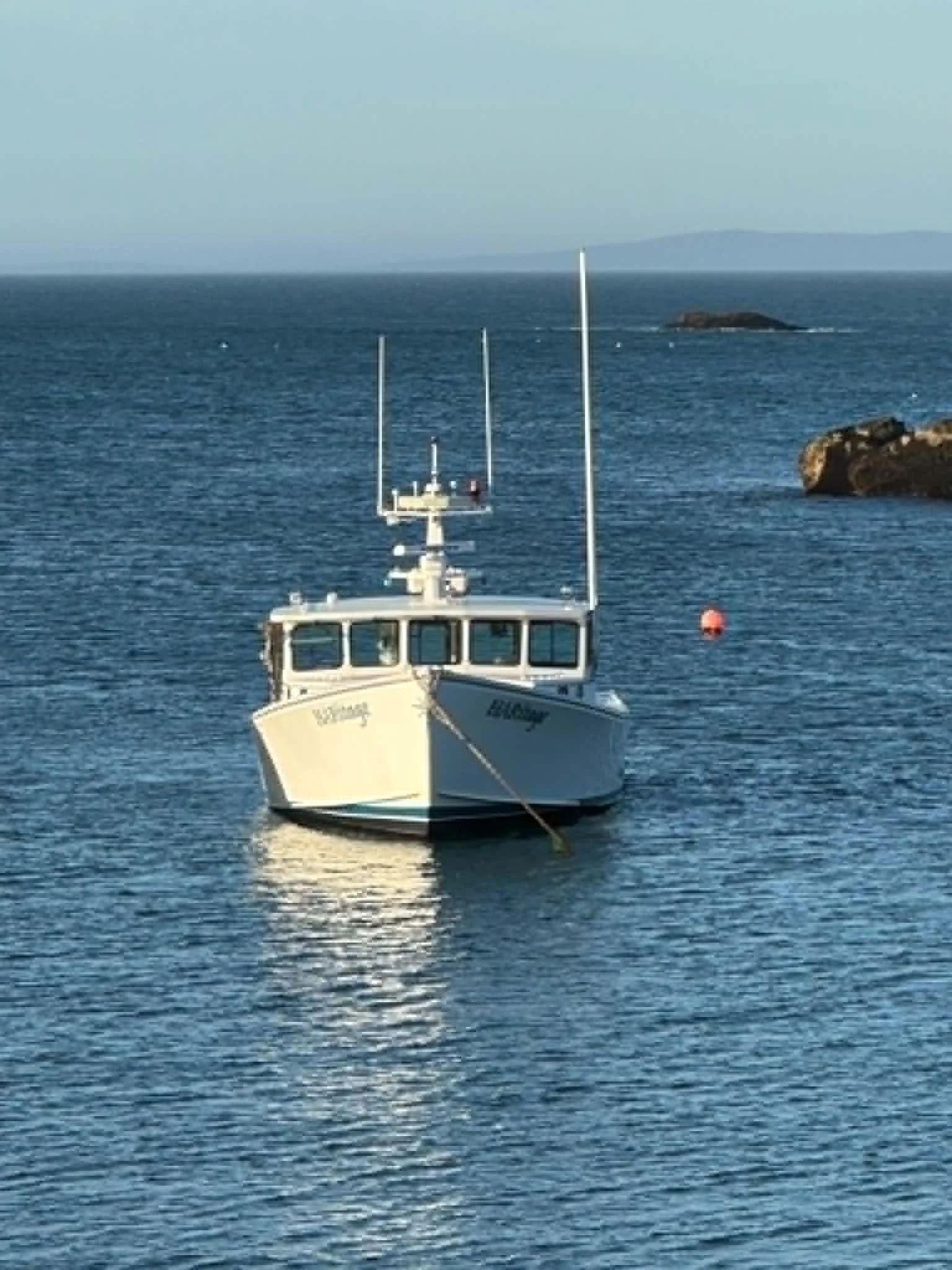 A boat in the water with a small island and distant land in the background.