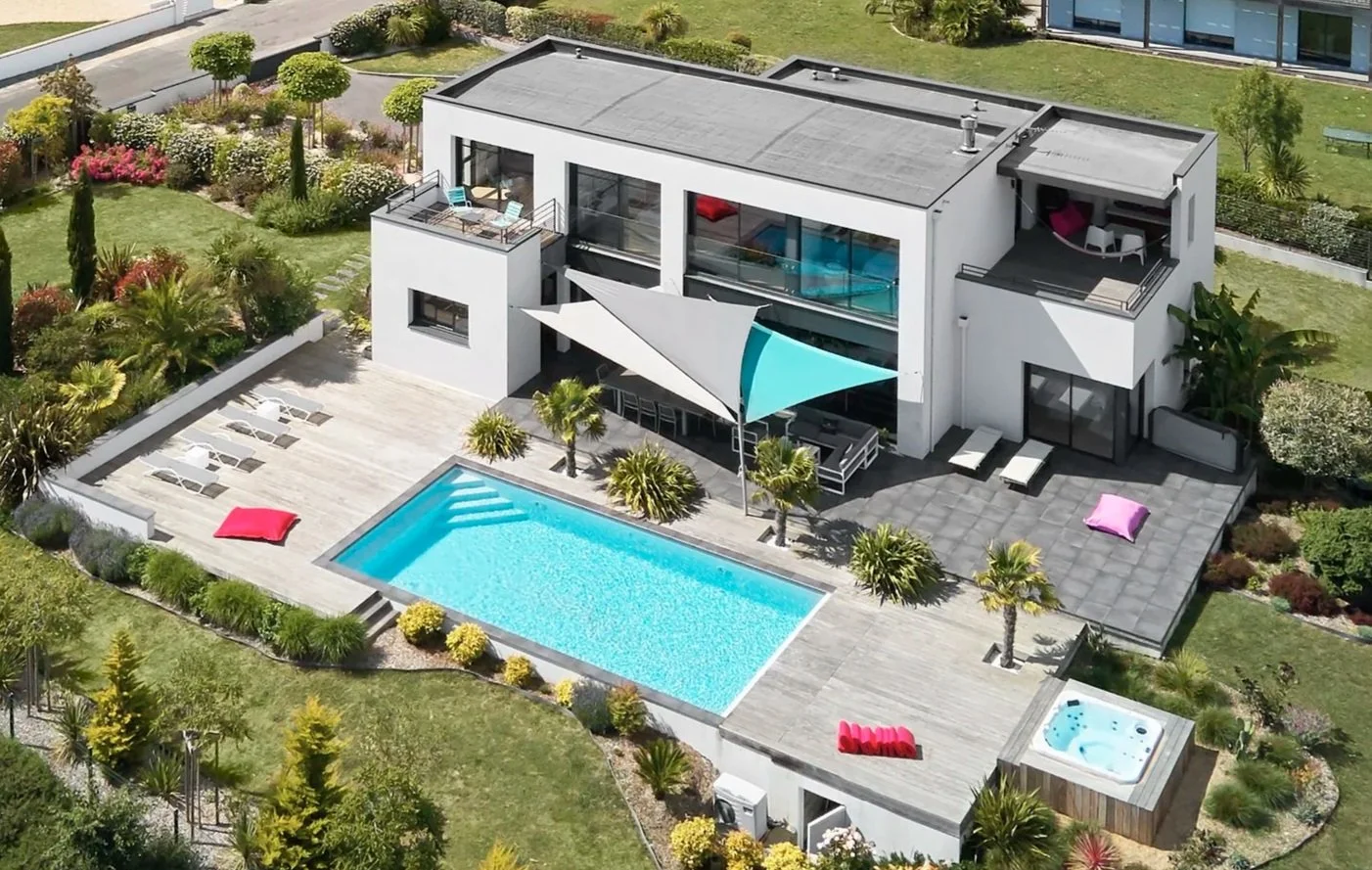 Vue drone d'une villa avec piscine, terrasse et jardin paysagé. Une composition équilibrée entre architecture moderne et cadre de vie paysager.