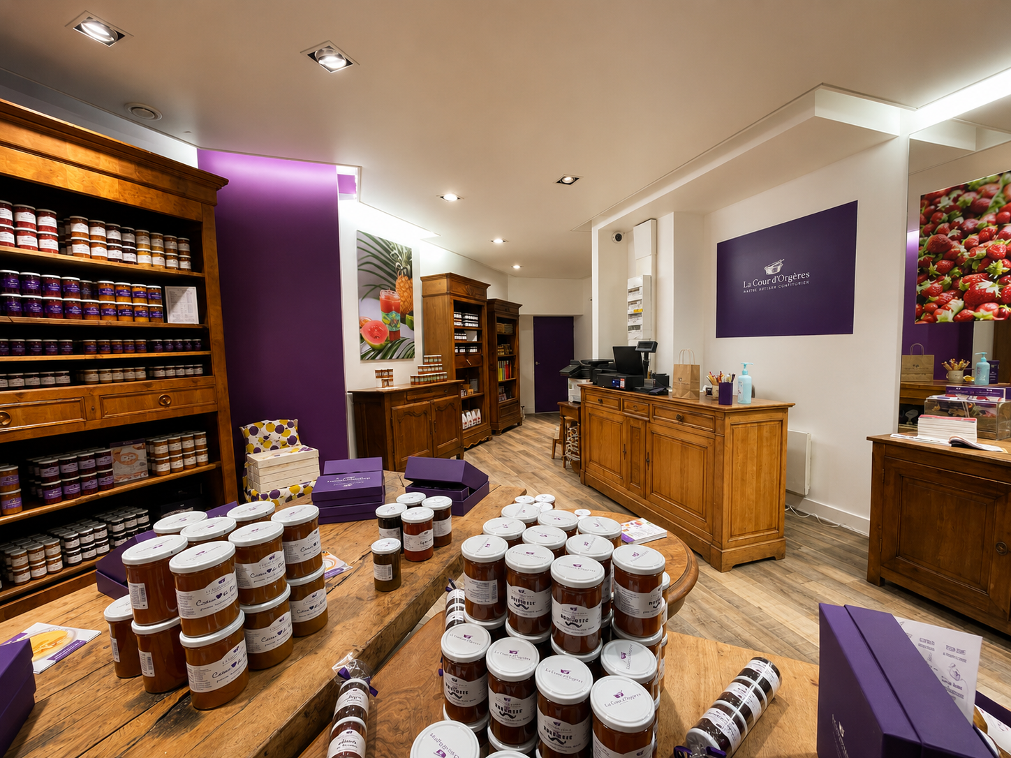 Mobilier bois massif, identité violette affirmée et mise en scène des produits pour une expérience client chaleureuse et gourmande.