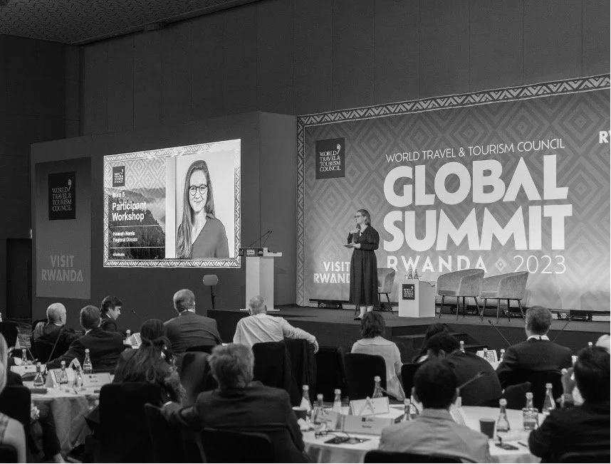 Black and white image of Hannah Norris on stage at WTTC Summit in Kigali leading a workshop
