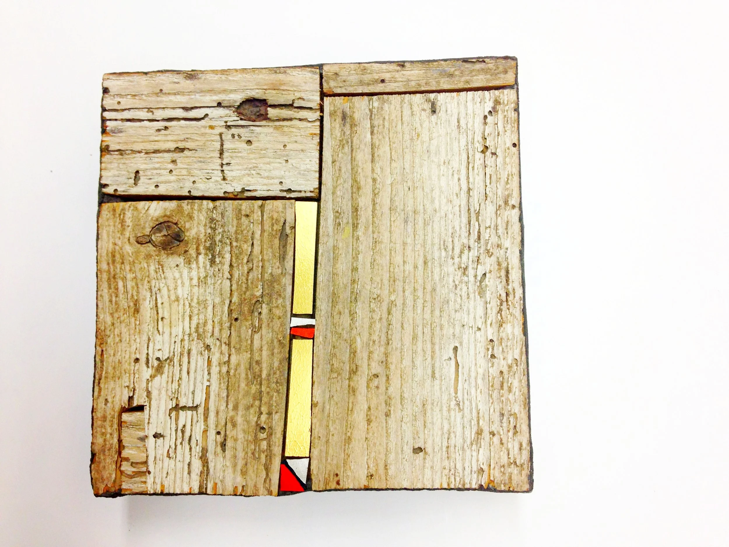 Tableau de bois en mosaïque de différentes tailles et couleurs, posés sur un fond blanc.