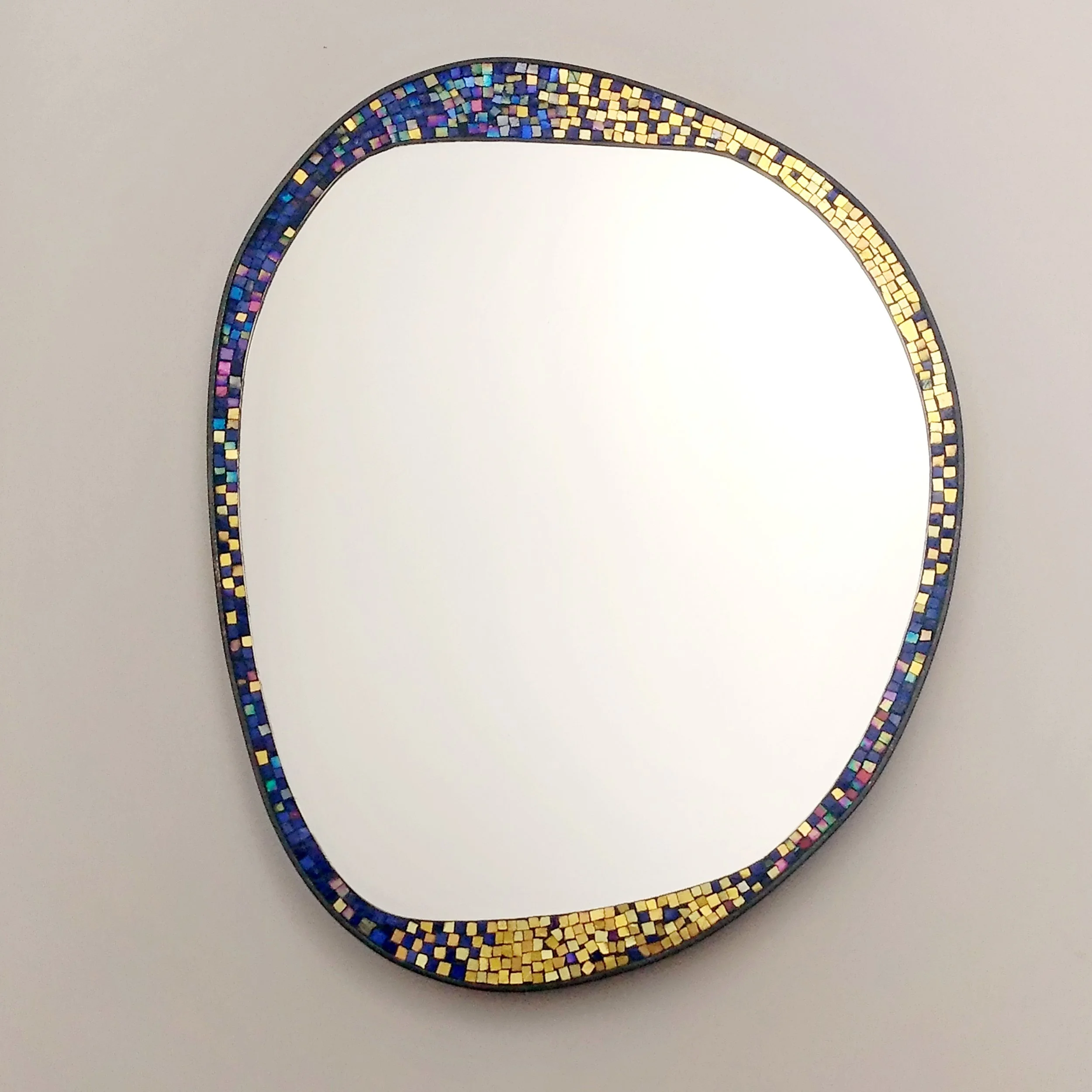 Miroir rond bordé de petits mosaïques colorées sur fond blanc.