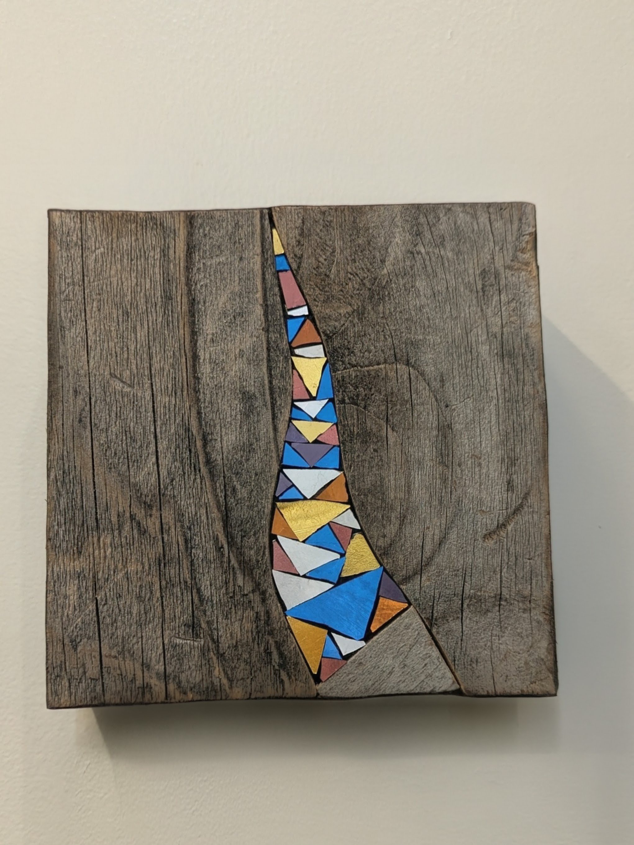 Une planche de bois avec une ligne de morceaux de verre colorés disposés en forme de couloir