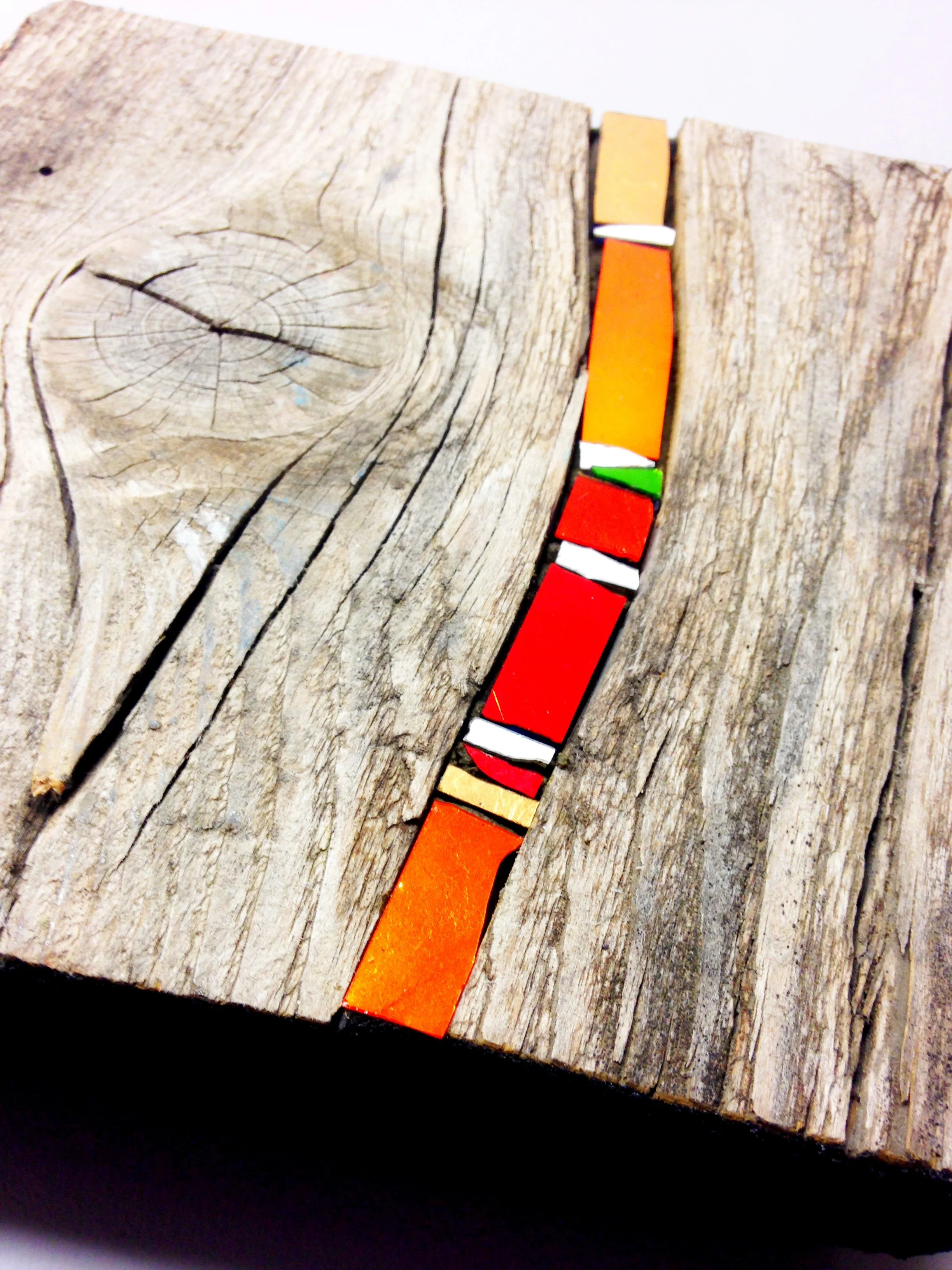 Une planche en bois avec de petites pierres colorées alignées au centre.